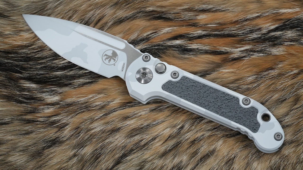Folding knife with a metallic blade and textured handle on a fur background