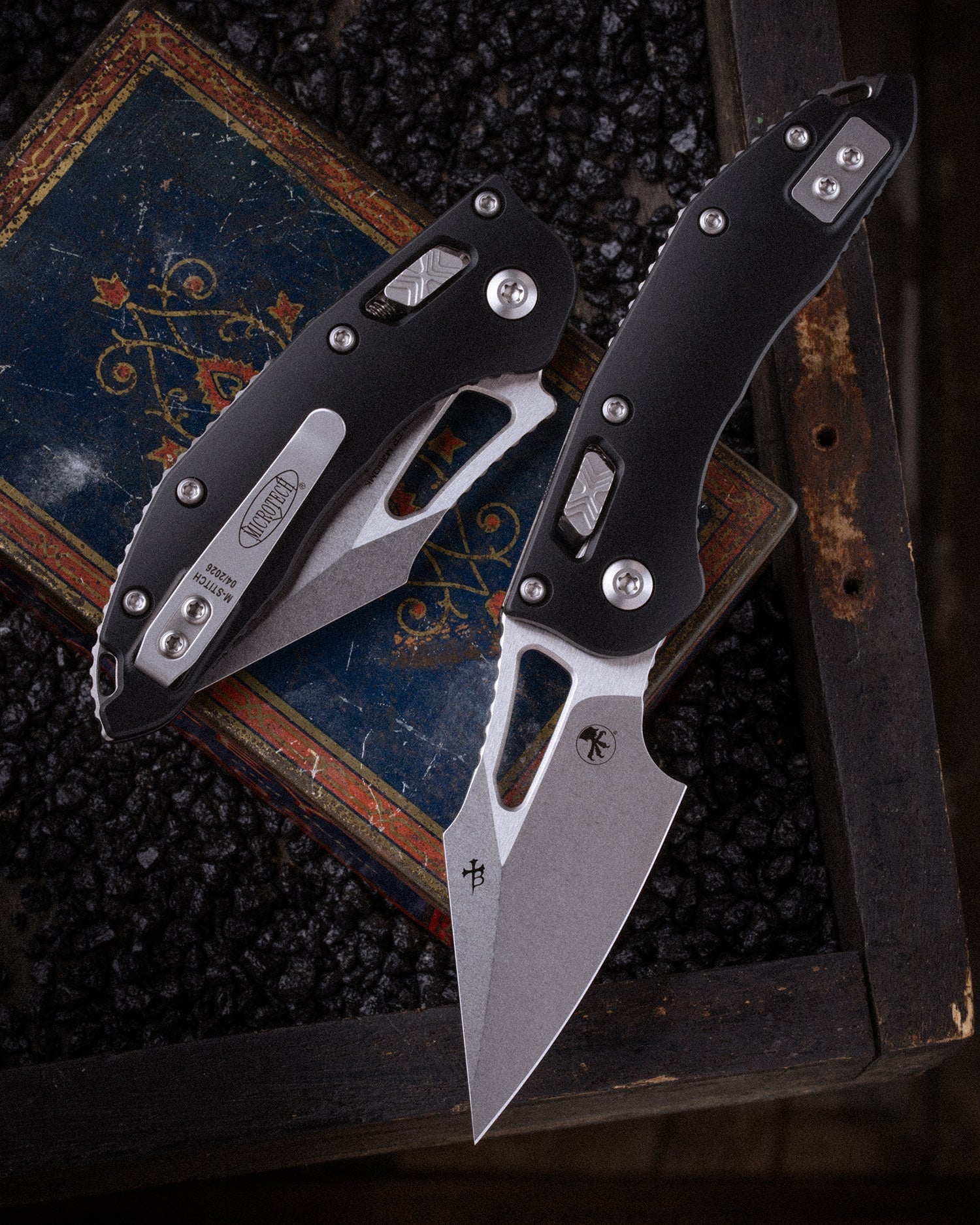 Two folding knives on a textured surface with a dark background