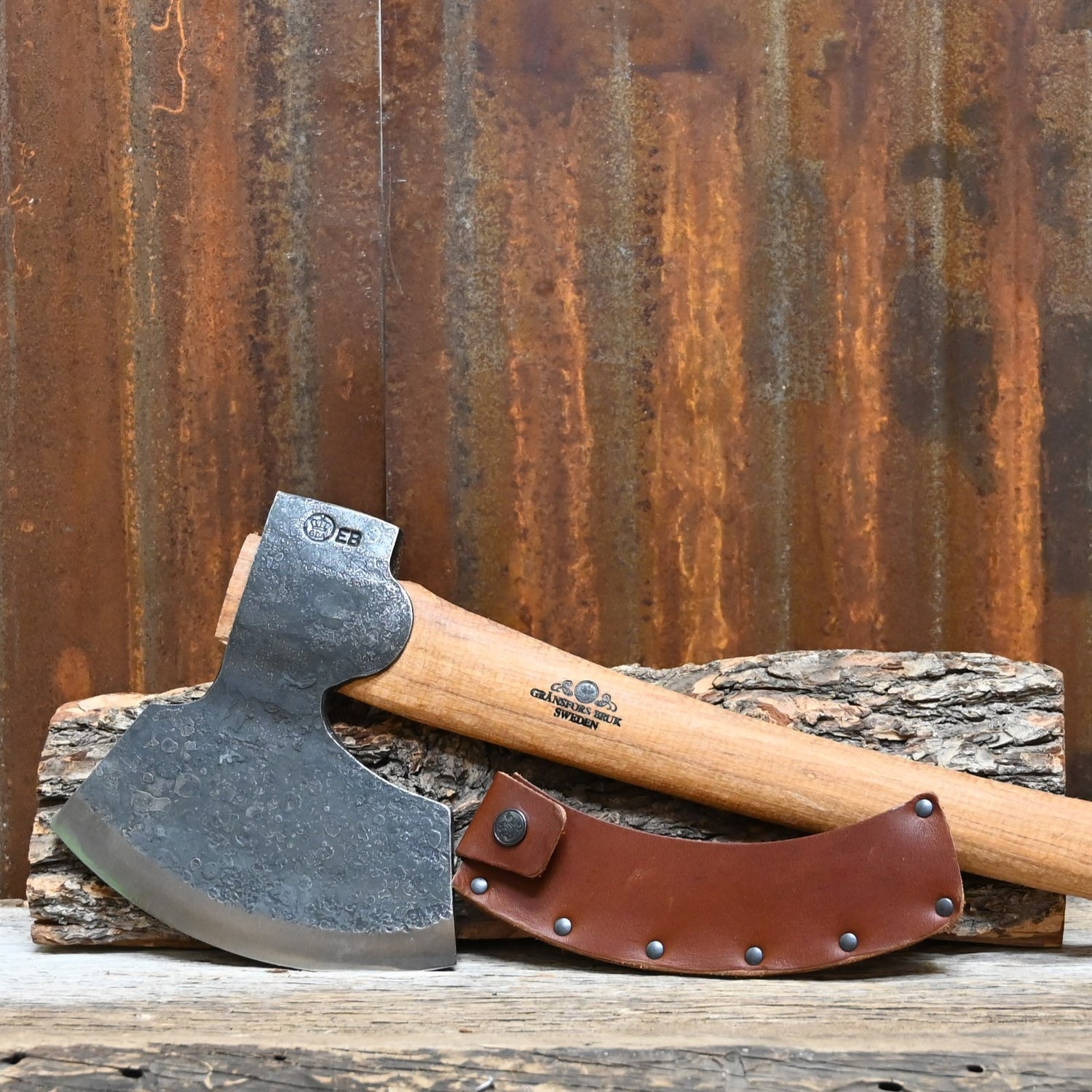 Axes with leather sheathes on a wooden surface against a rusty metal background