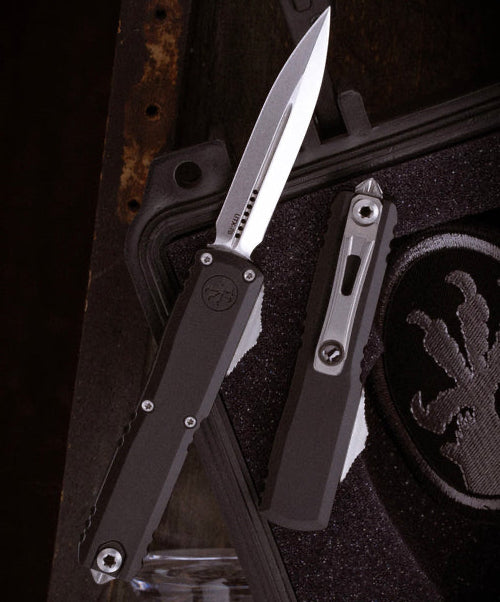 Black and silver pocket knife on a textured surface with a dark background