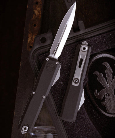 Black folding knife with a silver blade on a textured surface