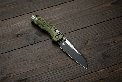 Folding knife with green handle and black blade on a white background