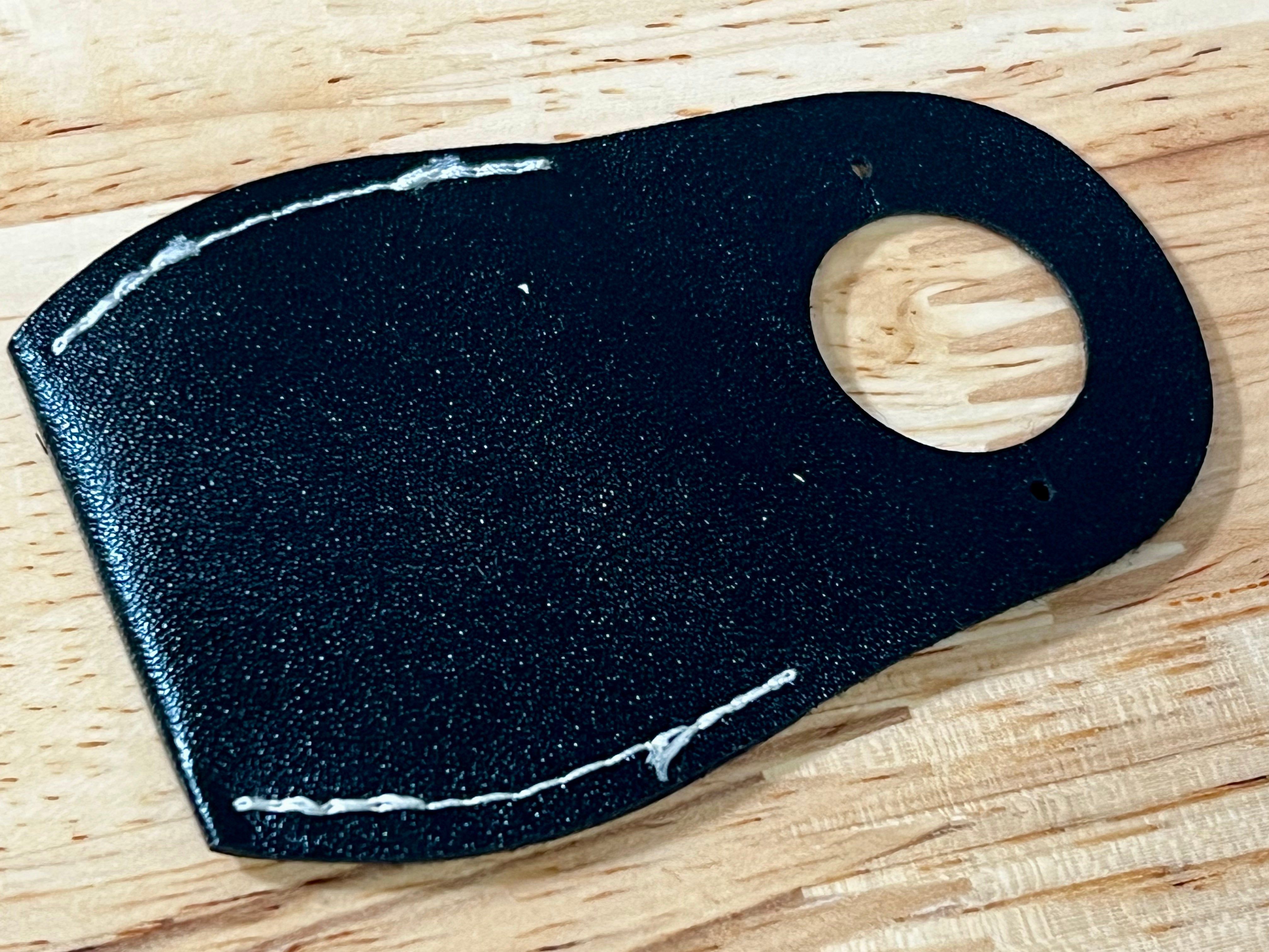 Black leather patch with a wooden button on a wooden surface