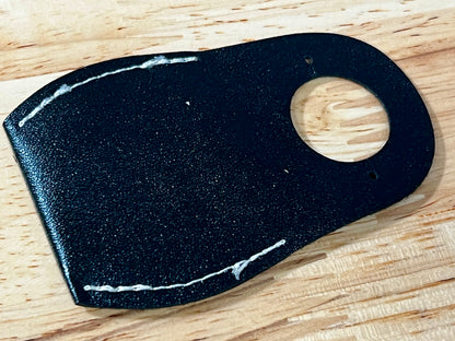 Black leather patch with a wooden button on a wooden surface