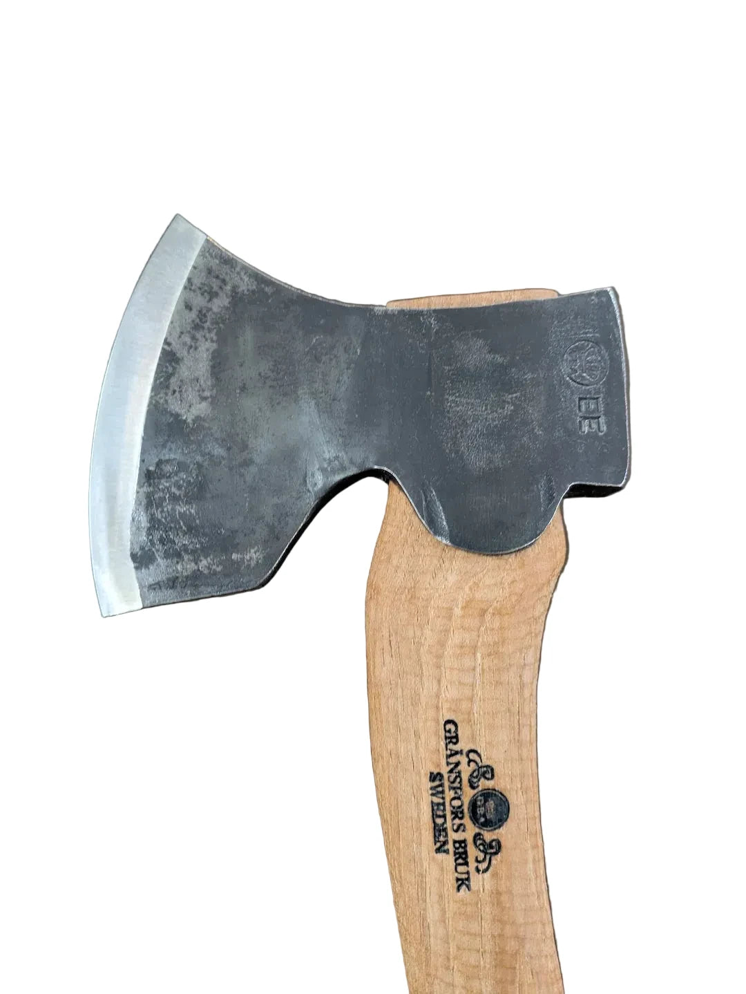 A close-up of a hand axe or hatchet with a dark steel head and a light natural wood handle, photographed against a plain brown background. The handle is printed with the brand name 'Grasshopper Brand'.